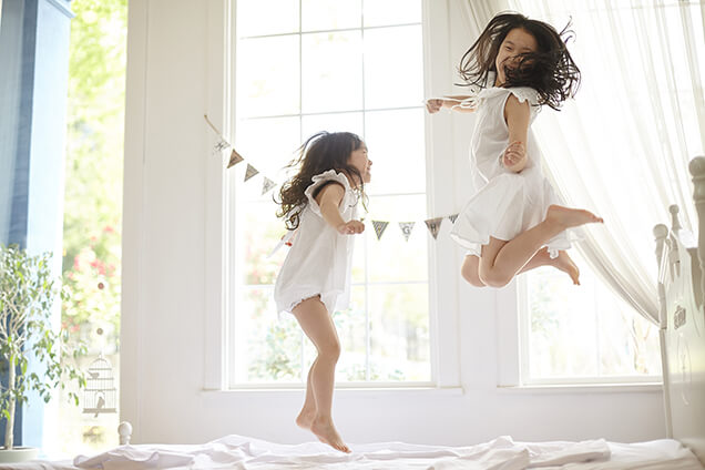 girls jumping on the bed enjoying indoor air quality