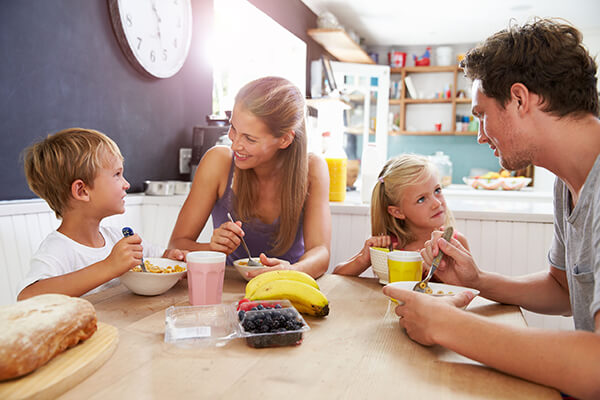 family talking and eating breakfast in kitchen