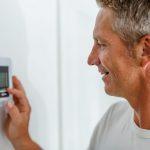 St. Louis man adjusting home thermostat