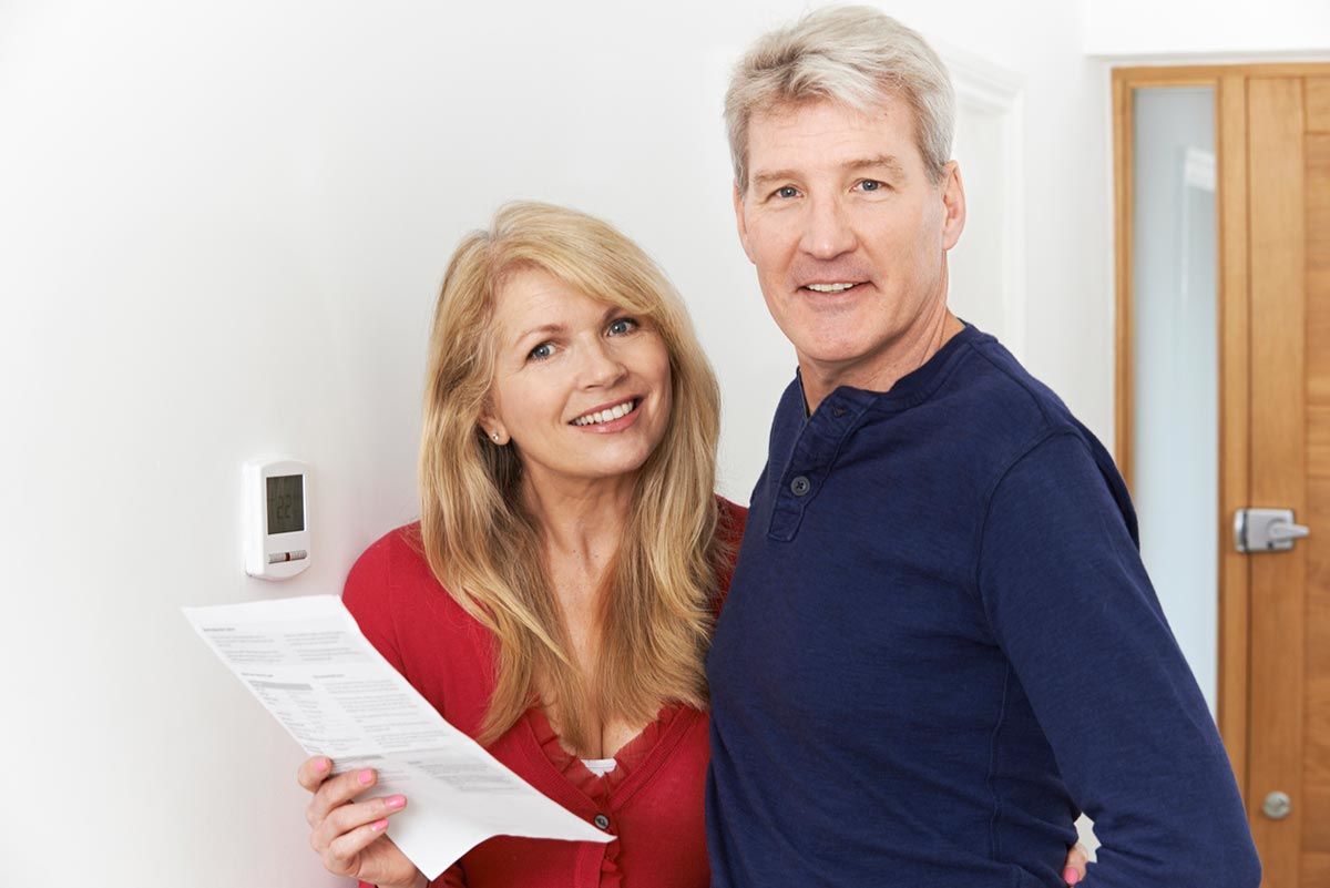 St. Louis couple next to thermostat with heating bill